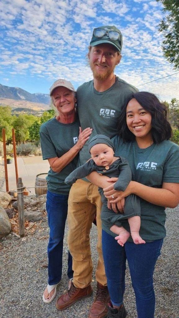 The three of us in matching farm shirts, the baby in the middle, the tractors and the peaks behind
