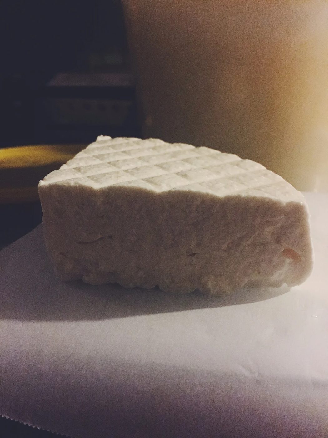 A crosshatched wedge of fresh feta resting on parchment